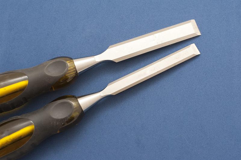 Free Stock Photo: Two DIY chisels for carpentry and woodworking of different sizes lying side by side on a blue background viewed from above with copyspace