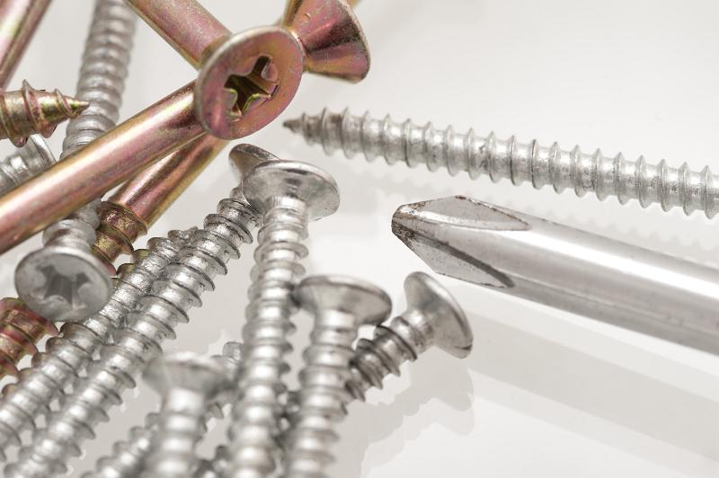 Free Stock Photo: Pile of threaded metal countersunk screws with a Philips head screwdriver on a white background for DIY and carpentry