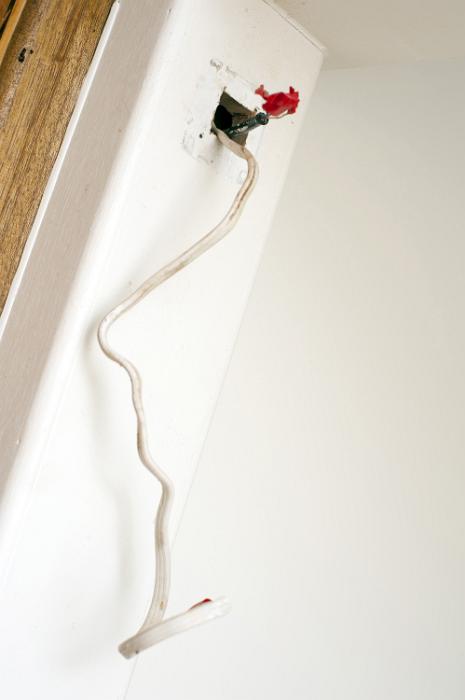 Free Stock Photo: DIY wiring in a renovation house project projecting from a small open access point in the wall and taped off at the end waiting for a fitting to be attached