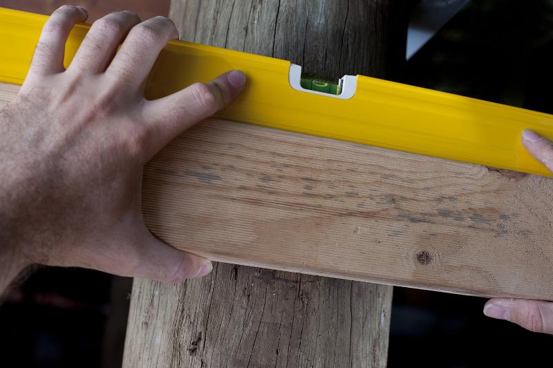 Free Stock Photo: Carpenter using a spirit level to adjust the horizontal angle on a plank of wood, close up of his hand and the bubble in the level