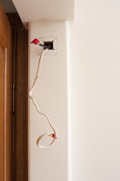 Free Stock Photo: Mains wiring for a domestic electricity supply with conduit alongside a door in a DIY and renovation concept entering on open access point in the wall