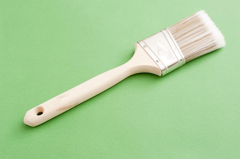 Free Stock Photo: Painters brush for interior decorating with a wooden handle lying diagonally on a green background with copyspace