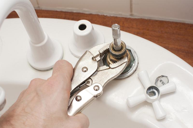 Free Stock Photo: Man using a mole grip wrench to dismantle a tap or faucet to replace a faulty washer in a DIY and renovation concept