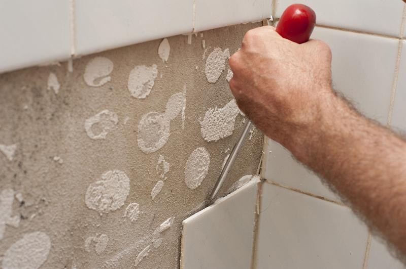 Free Stock Photo: Man prising loose old wall tiles with a screwdriver as he renovates his home in a DIY concept