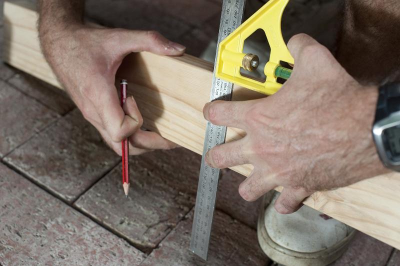 Free Stock Photo: Man marking a right angle cut on a plank of wood as he renovates his house, close up view of his hands and the tool