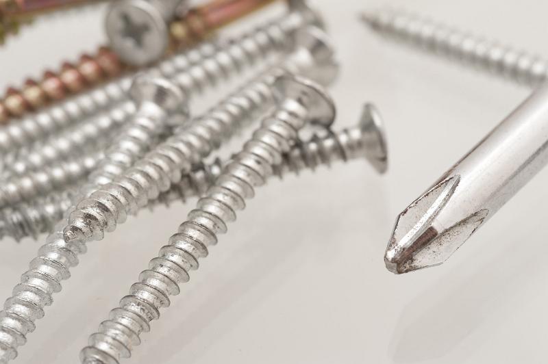 Free Stock Photo: Scattered pile of threaded metal screws with a Philips screwdriver in a conceptual image of DIY and renovation