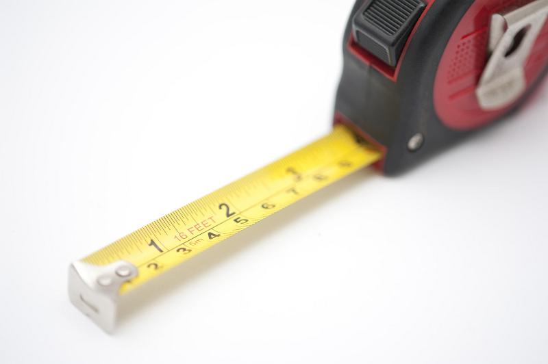 Free Stock Photo: Builders retractable tape measure with centimeters and inches on a white background with part of the tape extended to show the two scales