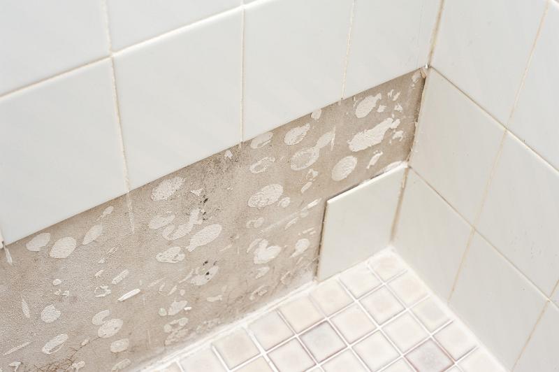 Free Stock Photo: Tiling a wall in a home showing the removal of old white wall tiles exposing the old adhesive before commencing with redecoration and renovation