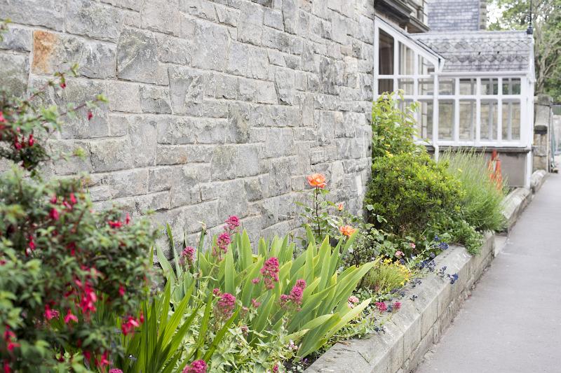 Free Stock Photo: Cottage country garden with summer flowers in a flowerbed along an old stone wall in a receding view