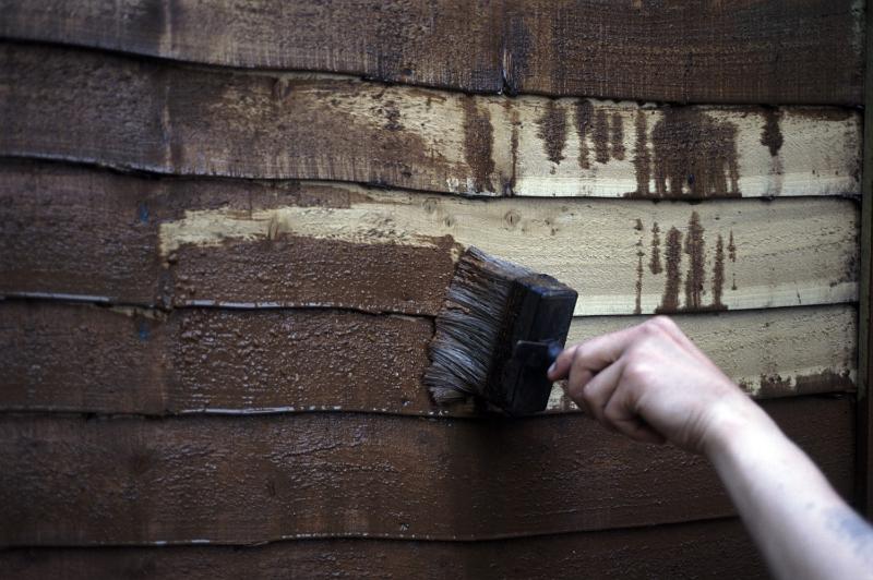 Free Stock Photo: Man painting an exterior timber building with creosote paint rich in phenols and creosols as a preservative and disinfectant for the wood
