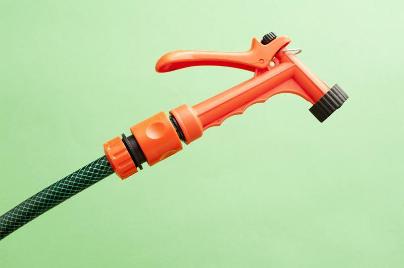 Free Stock Photo: Orange plastic garden spray nozzle on the end of a hosepipe for watering delicate seedlings and seed beds