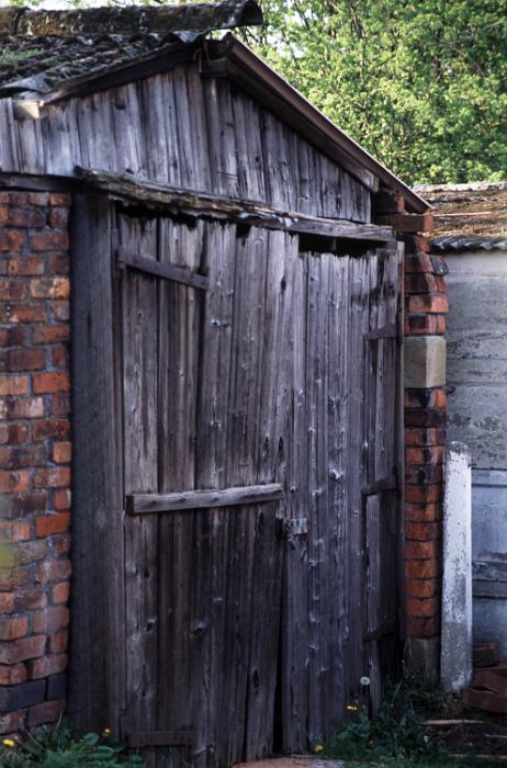 Free Stock Photo: Garden shed with brick walls and an old weathered wooden door and front facade