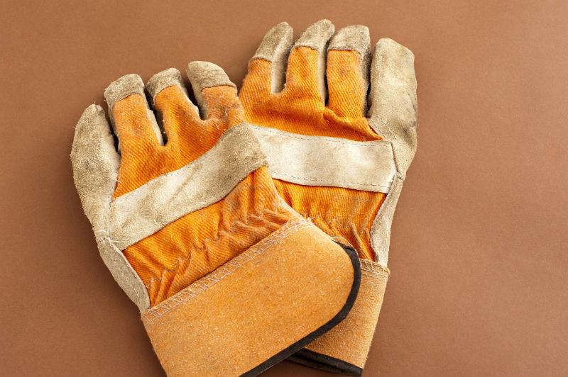 Free Stock Photo: Pair of old used gardening gloves lying on a brown background with copyspace