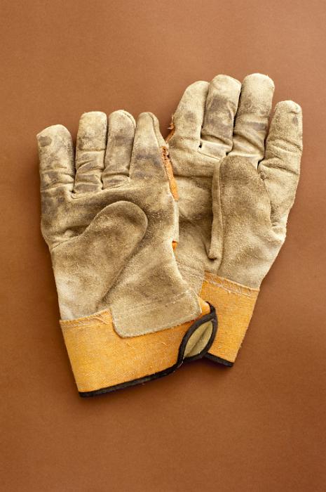 Free Stock Photo: Pair of used gardening gloves lying on a brown background, overhead view