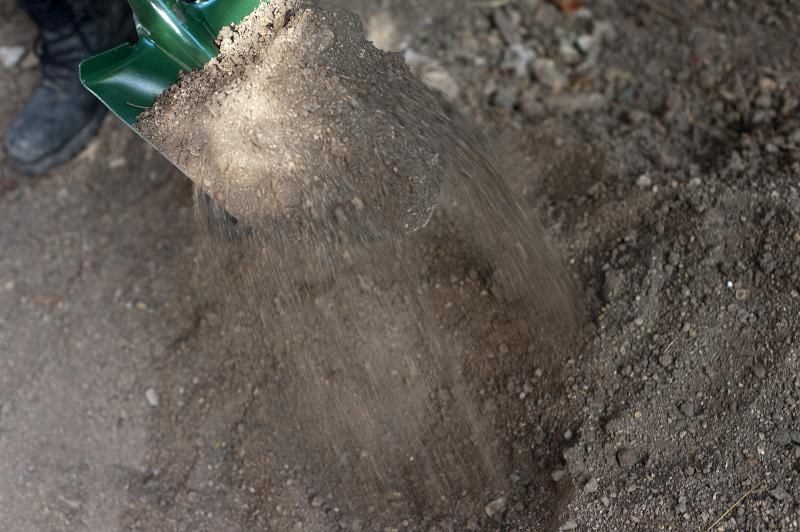Free Stock Photo: Digging garden soil with a spade with a close up view of earth trickling off the blade as it is raised