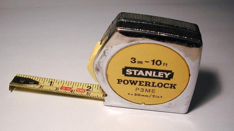 Free Stock Photo: Close Up of Profile of Yellow Stanley Tape Measure with Slightly Extended Ruler on White Background