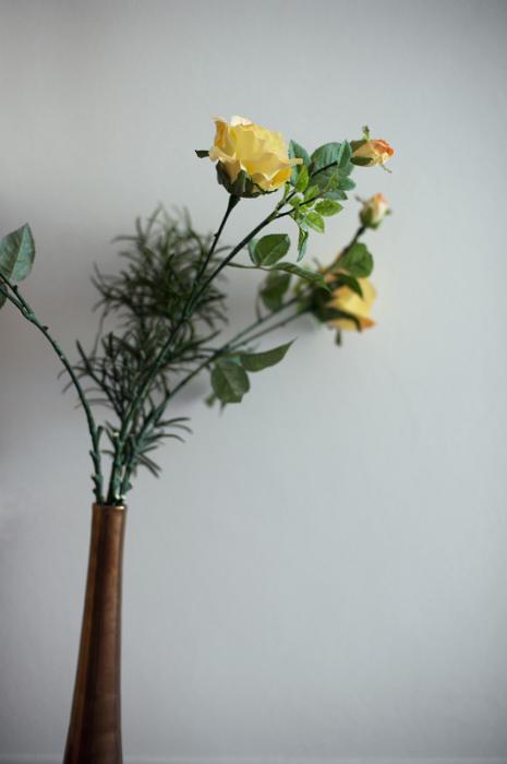 Free Stock Photo: Arrangement of fresh long stemmed yellow roses in a vase with decorative green foliage against a grey wall with copyspace
