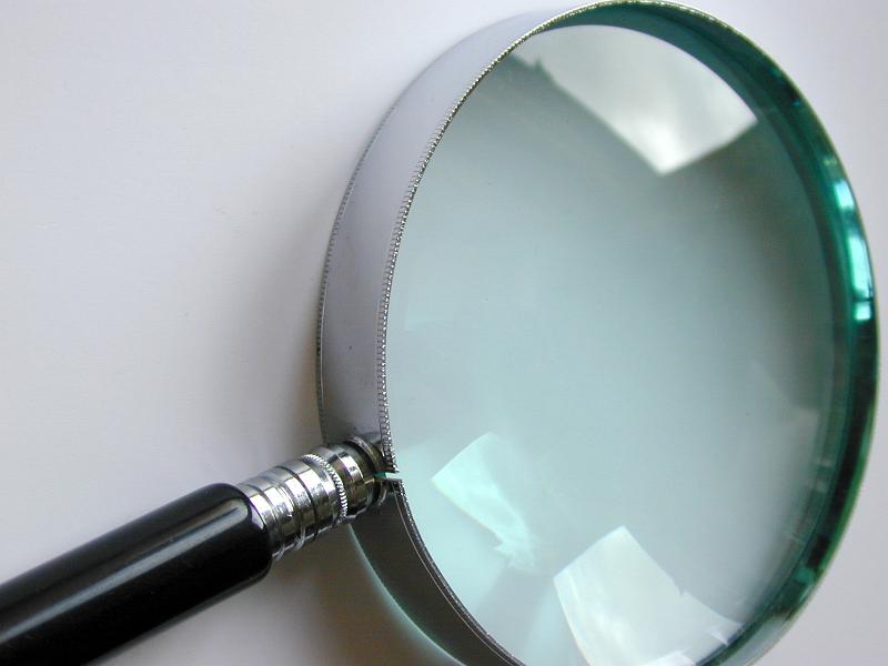 Free Stock Photo: Round magnifying glass with a metal frame laying obliquely away from the camera in a diagonal orientation in a conceptual image