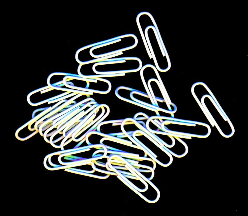Free Stock Photo: Scattered pile of white paperclips for filing documents and making attachments lying on a black background, overhead, view