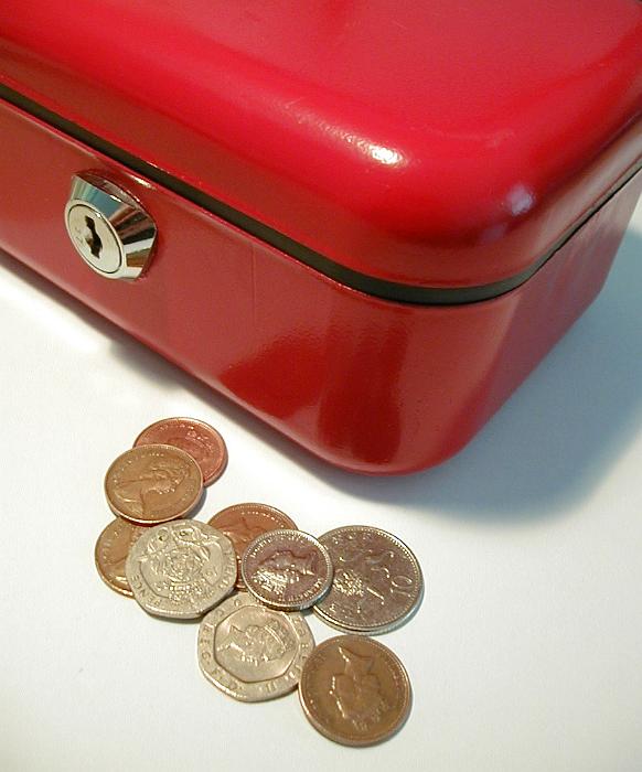 Free Stock Photo: Red metal cash box with a lock and loose coins lying alongside it, closeup high angle view of the corner