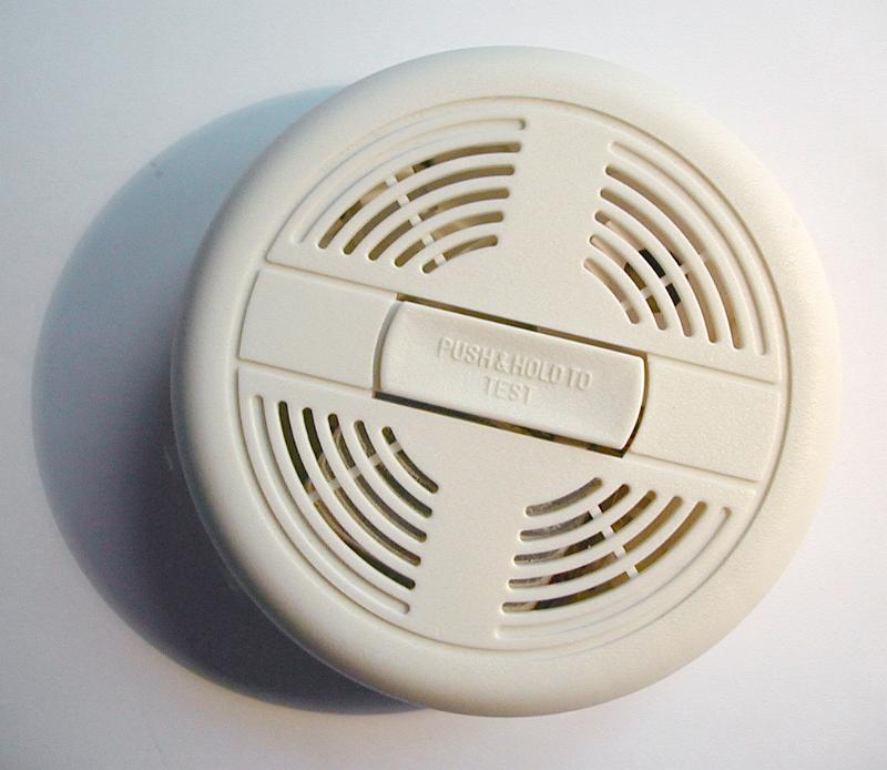 Free Stock Photo: Round white plastic cover of a smoke detector on a wall or ceiling to warn of a fire hazard, close up view