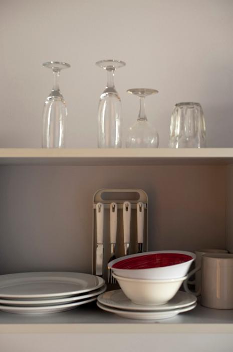 Free Stock Photo: Assorted crockery and glassware stacked on an open wooden kitchen shelf
