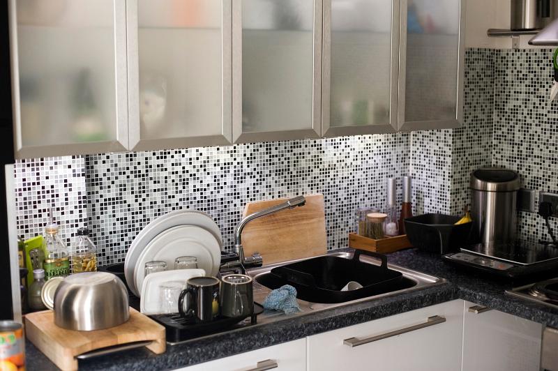 Free Stock Photo: Modern kitchen with a tiled mosaic splashback, glass fronted cupboards and under cupboard lighting above the sink, filled with small appliances on the countertops