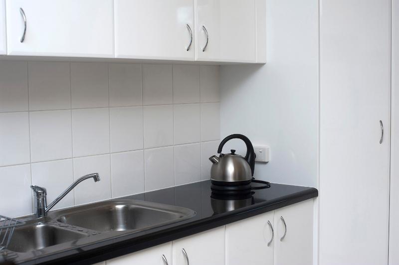Free Stock Photo: Kitchen worktop with kettle and stainless steel double sink and white cupboards.