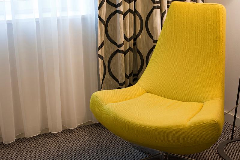 Free Stock Photo: Stylish retro styled yellow bucket chair in a modern living room with bold patterned drapes in an interior decor concept