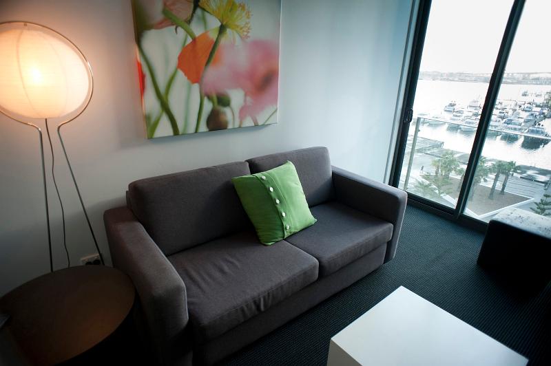 Free Stock Photo: Interior decor of a compact city apartment with a modern lounge with an illuminated standard lamp alongside a grey upholstered couch with modern artwork and a view window