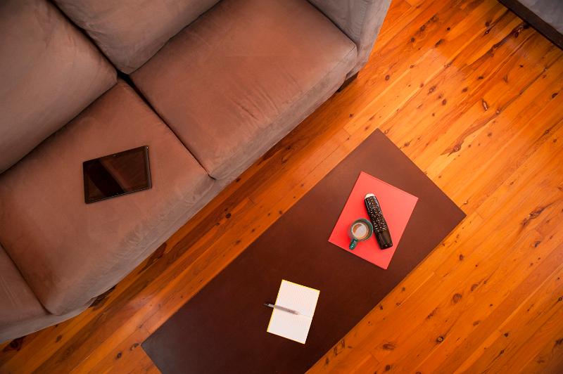 Free Stock Photo: View from above of a wooden coffee table and upholstered sofa on a hardwood floor in a living room