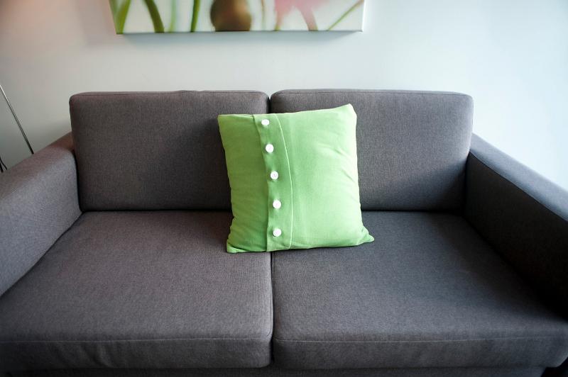Free Stock Photo: a plain grey sofa with a single green cushion and lots of space for copy