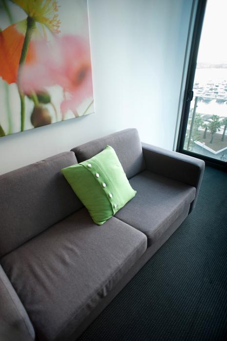 Free Stock Photo: Modern apartment living room with a generic upholstered grey couch alongside a view window