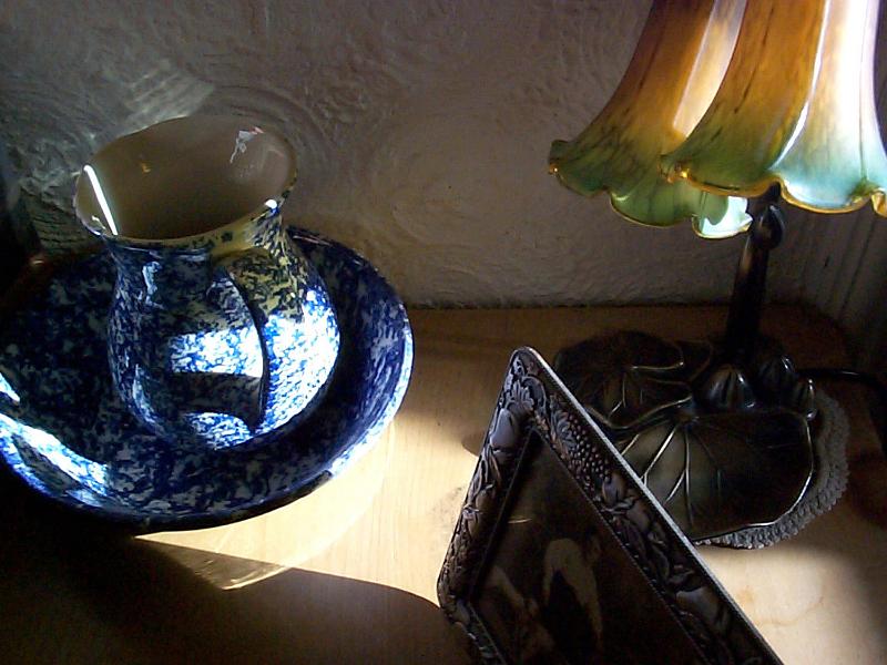Free Stock Photo: Old vintage objects with a blue and white pottery ewer and basin set, a sepia family portrait and Art Nouveau style lamp on a wooden cabinet
