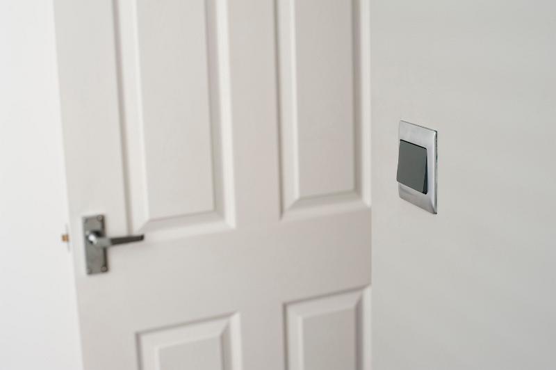 Free Stock Photo: Close up of an open white wooden paneled living room door with a light switch on the wall