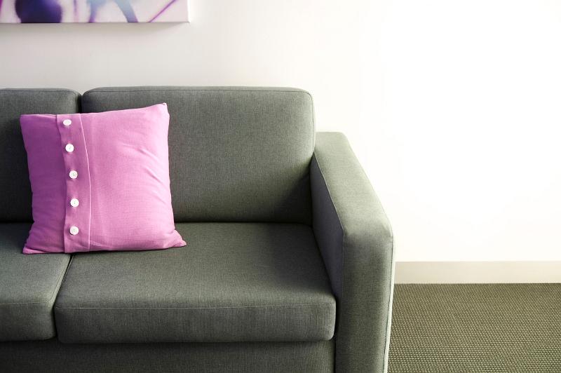 Free Stock Photo: Pink cushion with button decoration on a comfortable neutral couch or settee against a white wall in daylight