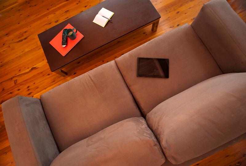 Free Stock Photo: Empty comfortable upholstered brown sofa from above with a coffee table on a plain hardwood floor