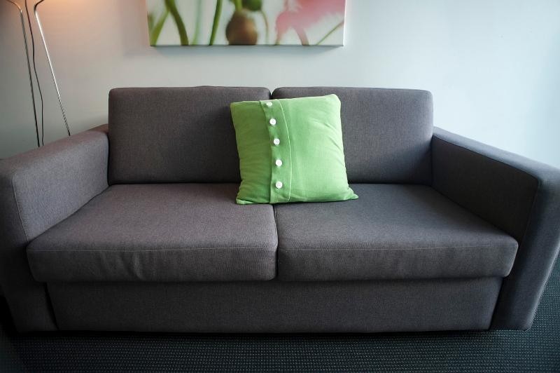 Free Stock Photo: Wide angle close up view of an empty upholstered modern grey couch with a green cushion