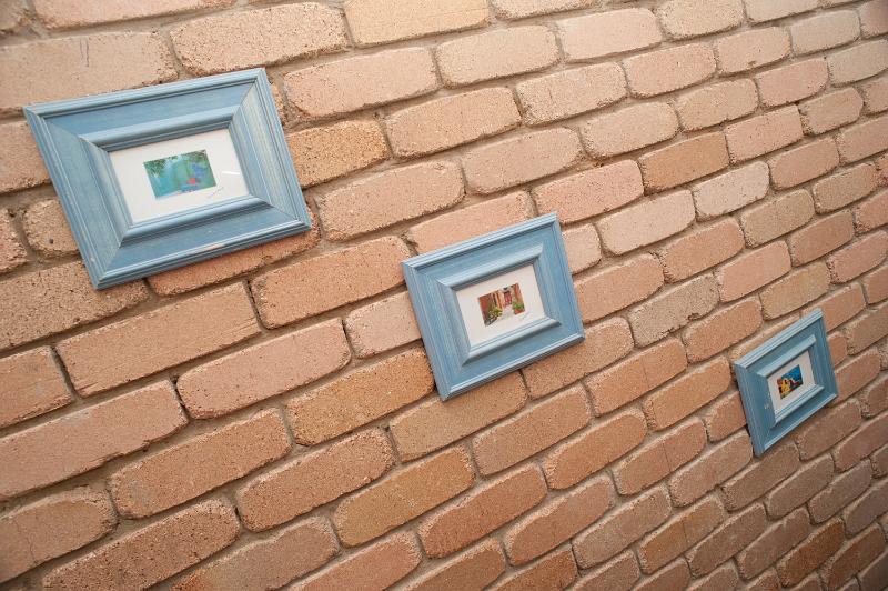 Free Stock Photo: Series of three wall pictures in a diagonal display on a face brick wall taken at an oblique perspective