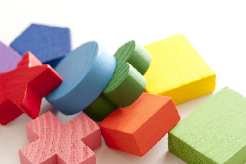 Free Stock Photo: Colorful educational wooden toy blocks in a variety of different basic geometrical shapes lying in a heap on white