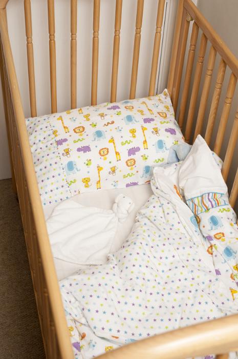 Free Stock Photo: Empty wooden cot or crib for a young child with decorative linen viewed high angle