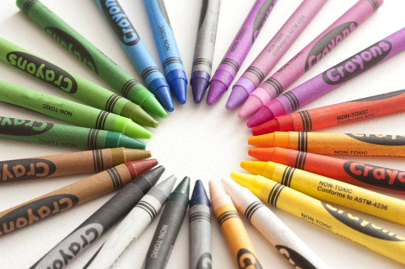 Free Stock Photo: Artistic circular arrangement of wax crayons in the colors of the spectrum with their tips converging in the centre of the frame around blank white copy space, viewed from above