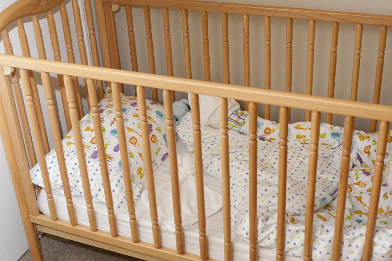 Free Stock Photo: Looking Down at Empty Crib with Rumpled Bedding Decorated with Playful Pattern in Child Bedroom