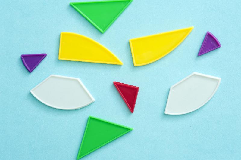 Free Stock Photo: Set of colorful plastic shapes for teaching kids to match shapes to cut outs in a puzzle arranged on a turquoise blue background