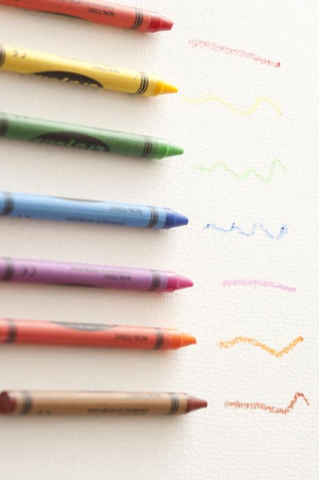 Free Stock Photo: Row of colored wax crayons in the colors of the spectrum or rainbow with hand drawn squiggles showing the colors on white, overhead view