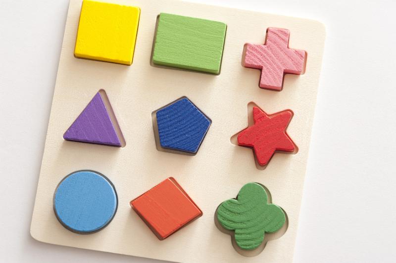 Free Stock Photo: Kids educational wooden toy shapes puzzle with nine colorful basic shapes placed in matching cut outs on a board, high angle view