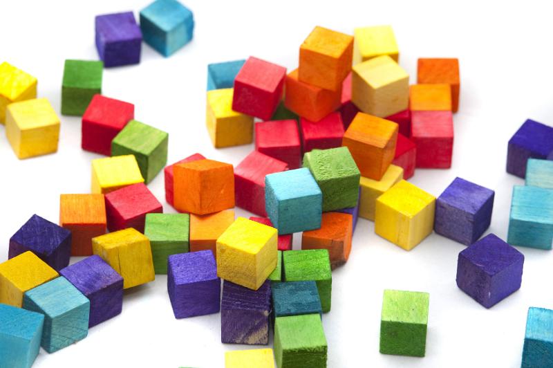 Free Stock Photo: Bright multicolored wooden toy blocks in the colors of the rainbow scattered in a heap on a white background