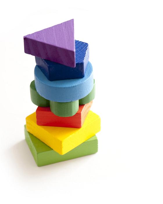 Free Stock Photo: Stack of colorful wooden toy blocks in an assortment of different basic shapes for teaching children over a white background with copy space