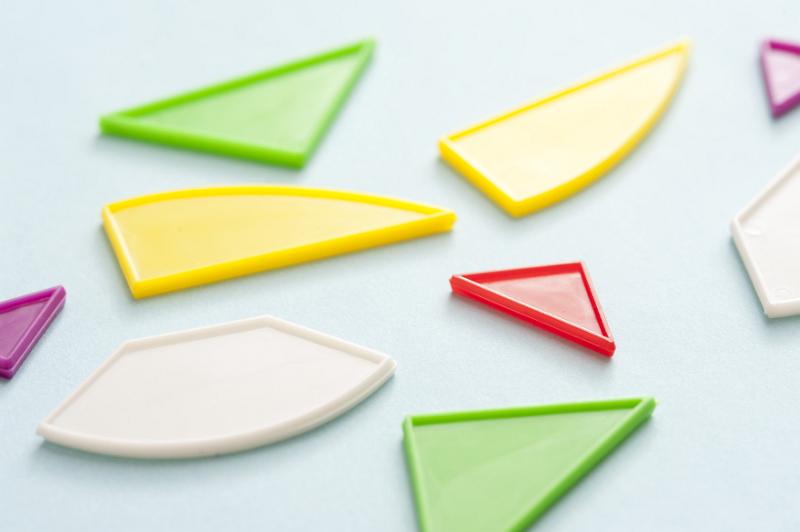 Free Stock Photo: Different shapes in colorful plastic for teaching kids to recognise the difference and place them inside a corresponding cut out puzzle, scattered on a light blue surface
