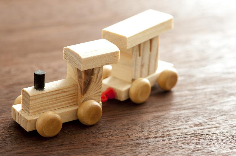 Free Stock Photo: Kids wooden toy train made of pine with an engine pulling a single carriage on a wooden table, high angle view